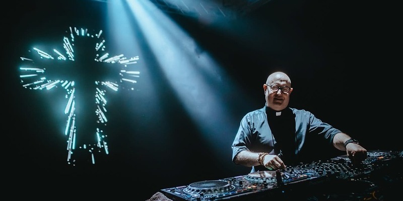 Padre Guilherme am DJ Pult mit Kreuz im Hintergrund