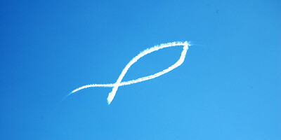 Christus-Symbol als weiße Lichtspur im blauen Himmel