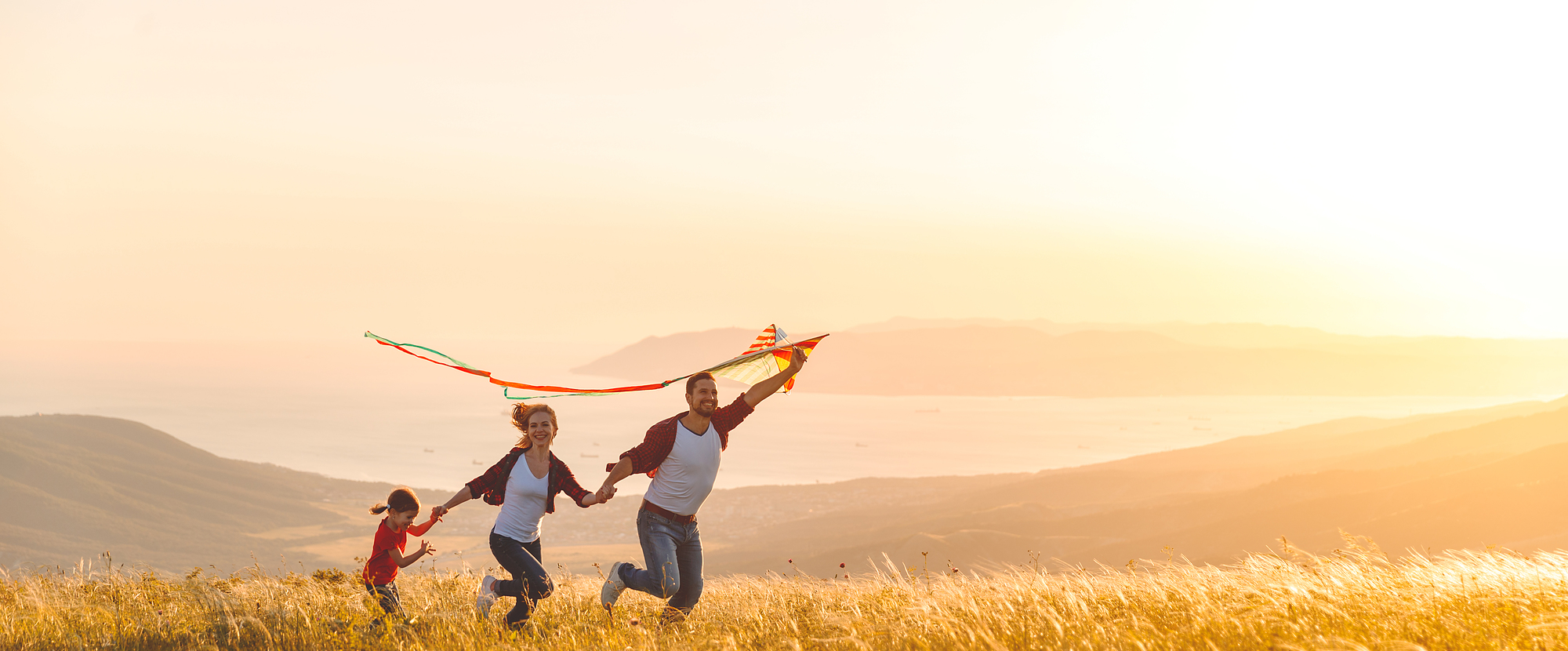 Happy family father,  mother and child daughter launch a kite on nature at sunset