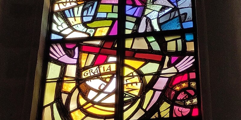 Ein buntes Glasfenster im Eisenstädter Dom, zeigt Maria, wie sie preisend ihre Hände hebt.