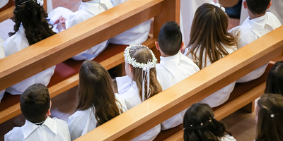 Children on the first holy communion in the church. View from above of children sitting in the bench during the first holy communion mass. 